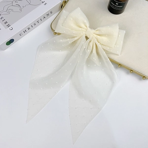 Close-up of cream white chiffon bow hair clip with delicate polka dots and long ribbon