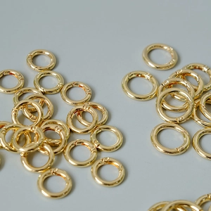 Detailed view of polished golden metal O-rings with spring clip mechanism for DIY accessories