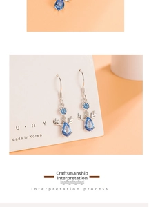 Detail view of silver reindeer horn earrings with drop-shaped sky blue gemstones