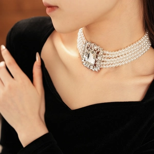 Detail of multi-layer pearl choker necklace featuring a central square crystal on a model