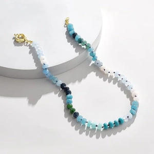 Close-up of bohemian beaded necklace with blue and green stones and gold metal clasp