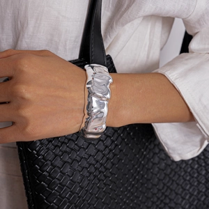 Macro shot of silver liquid metal texture on the wide irregular open cuff bracelet