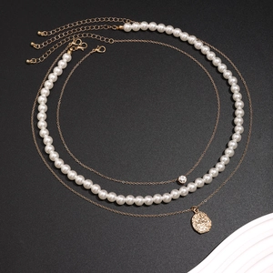 Drielaagse herenketting met witte parels en gouden hangers op zwarte achtergrond