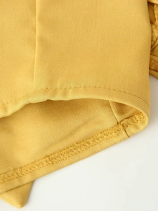 Makro-Detail von gelbem Twill-Stoff mit präzisen Nähten und Saumverarbeitung
