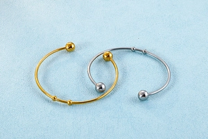 Detailed view of polished gold and silver stainless steel bangles on blue textured surface