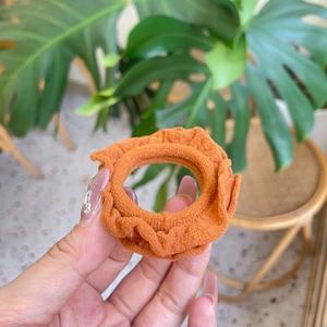 Close-up of orange ruffled fabric hair scrunchie showing detailed pleated texture