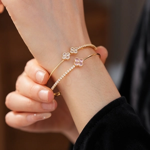 Close-up of a double-layered gold bracelet with zircon flowers on a woman's wrist