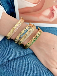 Vue détaillée de quatre bracelets dorés superposés ornés de zircons colorés variés