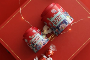 Close-up of red metal gift tins with floral illustrations and Forest's Secret logo text