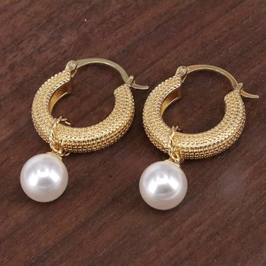 Detail of gold leverback earrings featuring granulation texture and a white pearl drop