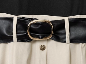 Détail de la ceinture en cuir noir avec boucle dorée sur le tissu beige de la robe