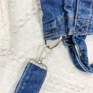 Detail of blue denim bag strap with silver metal swivel hook and yellow stitching