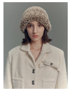 Detail of faux fur winter hat with texture of premium cream jacket and bow accessory