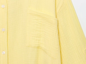 Detail of light yellow cotton linen shirt featuring gauze texture and white buttons