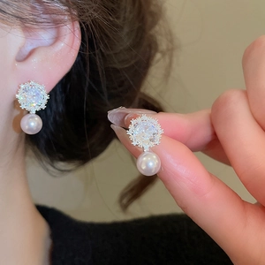 Close-up of elegant snowflake zircon earrings with a soft pink pearl drop detail