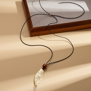 Detail view of a gold leaf pendant necklace with wood bead and black cord chain