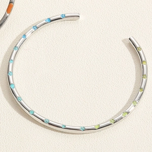 Détail d'un bracelet argenté avec fleurs en émail coloré et motifs de cœur sur papier