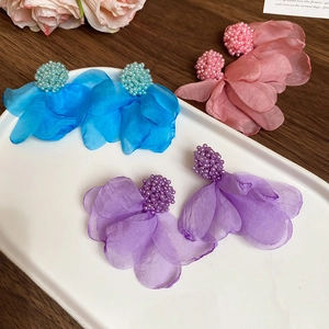 Detail view of floral fabric cluster earrings in blue, pink and purple on a white tray