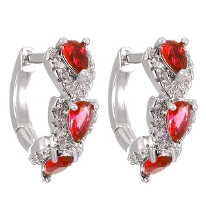 Close-up of silver earrings with pear-cut red zircons and sparkling white crystals