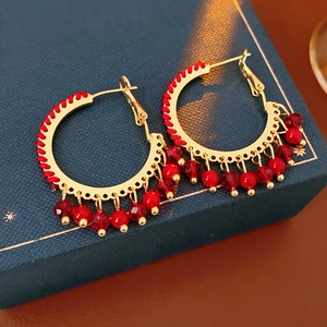 Dettaglio di orecchini vintage dorati con perline rosse su scatola portagioie blu