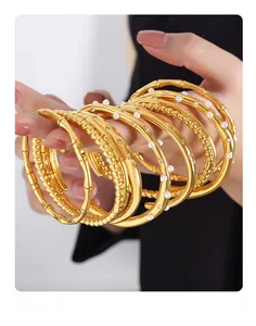 Detail of layered gold titanium steel bracelets with pearl and bamboo texture accents
