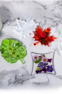 Macro view of leaf-shaped silicone coaster molds with floral resin crafts on marble