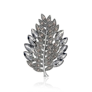 Detailed macro view of silver leaf brooch with dark grey crystals and rhinestones