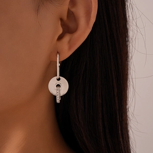 Close-up of model wearing geometric silver earrings with diamond-encrusted circular discs
