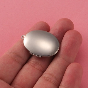 Macro shot showing the actual size of a 316L stainless steel oval locket on a hand