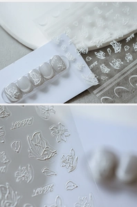 Macro detail of 5D embossed white nail stickers with 3D floral and butterfly textures