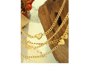 Detail of vintage 18K gold heart pendant layered on classic curb chains over rustic wood