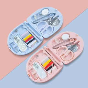 Detailed view of pink and blue portable sewing kits featuring needles, thread, and scissors