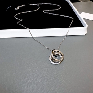 Macro detail of silver interlocking triple ring pendant on a fine link chain necklace