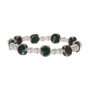 Detailed view of white faux pearl beads and dark green ceramic flower charms on bracelet