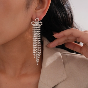 Gros plan de boucles d'oreilles à pompons fleuris avec de longs strass sur l'oreille