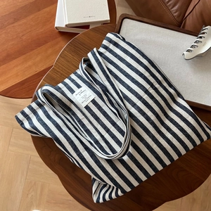 Vue à plat du grand sac fourre-tout en toile à rayures bleu marine et blanc sur bois