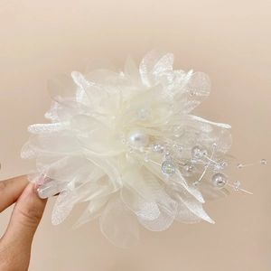 Close-up of white organza flower hair claw with oversized pearl and beaded filaments