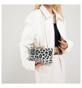 Detail of leopard print evening clutch bag with gold chain strap on white leather jacket