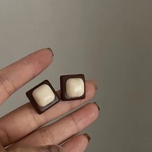 Gros plan sur des boucles d'oreilles carrées rétro, blanc crème avec cadre en résine