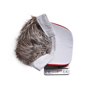 White baseball visor with grey-brown wig hair showing weight on a digital scale