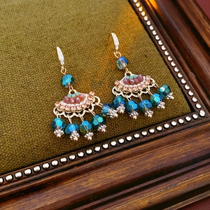 Detailed close-up of vintage gold tassel earrings with zircon and teal beaded fringe