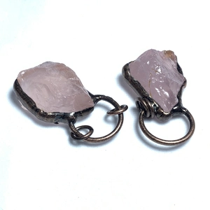 Dettaglio di pietre grezze rosa con avvolgimento artigianale in metallo bronzato