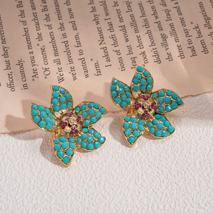 Retro gold flower earrings with blue petals and purple crystals on a vintage book background