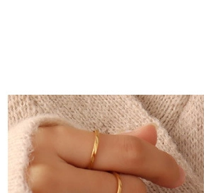 Close-up of textured gold ring on hand with cream knit sweater background