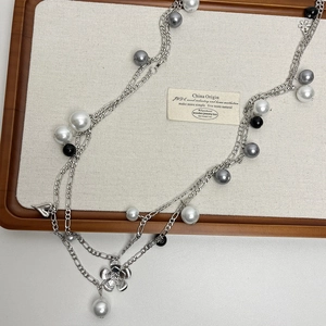 Detail of multi-layer gray pearl necklace with floral and heart pendants on tray