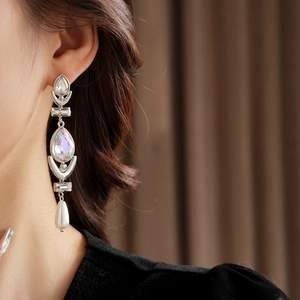 Detailed shot of long silver tassel earring with crystal accents and pearl on model