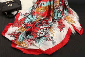 Detailed close-up of a floral satin square scarf with elegant red borders and smooth texture