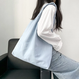 Detailed lifestyle shot of blue canvas tote bag with white polka dots on a shoulder