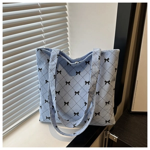 Dettaglio della borsa tote in velluto a coste azzurro con motivi a rombi e fiocchi