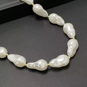 Detail of baroque pearls necklace with golden beads on grey textured background